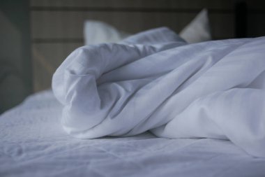 Yumuşak, beyaz bir battaniye sessiz bir odada buruşuk bir çarşafın üzerinde duruyor..