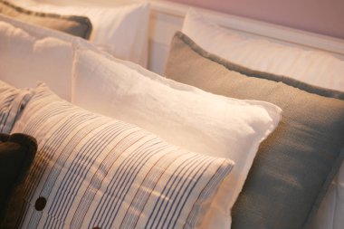 Rahat bir yatakta düzgünce dizilmiş yumuşak yastık koleksiyonu..