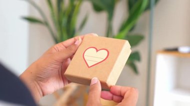 Bir insan içinde bitkilerle çevrili kalp tasarımı olan küçük bir hediye kutusu tutar..