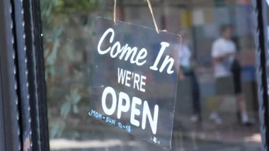 Sıcak, açık bir tabela bir dükkana asılıyor, şehirde müşterileri ağırlıyor..