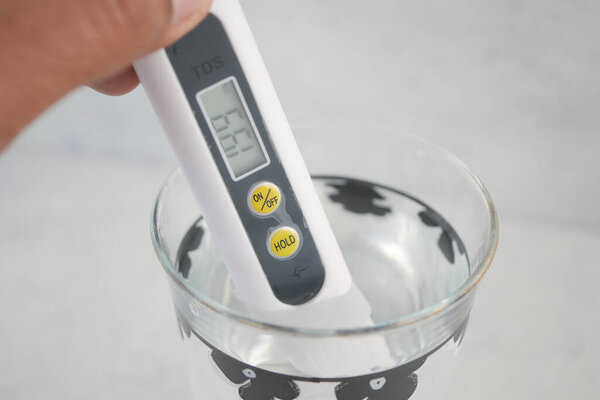 Измеритель TDS используется для проверки качества воды в стеклянной чаше.