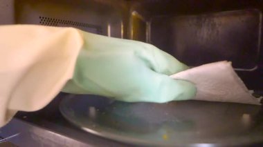 Eldivendeki bir el mikrodalganın içini siler..