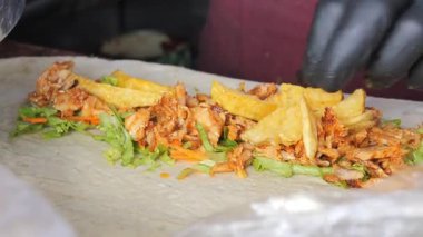 Genç adam lezzetli tavuk dürümü hazırlıyor. .