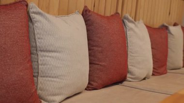 Sıcak renklerde yumuşak yastıklar kapalı bir bankta oturur..