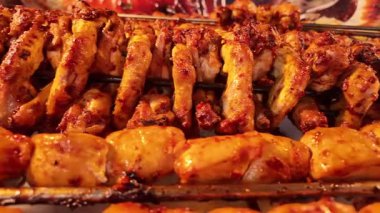 Sulu tavuk kanatları ve et şişleri hayat dolu bir sokak fuarında pişirilir..