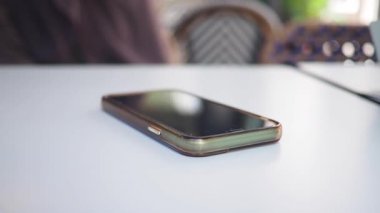 Çocuk eli masaya uzanmış akıllı bir telefona uzanır. .