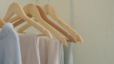 Dolaptaki ahşap askılara düzgün bir şekilde asılmış giysiler..