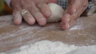 Eller hamuru sıcak bir mutfakta un kaplı bir yüzeyde çalışır..