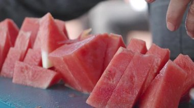 Tedarikçiler kalabalık bir pazarda müşteriler için karpuz dilimler.