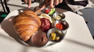 Bir insan taze kruvasanın tadını çıkarıyor lezzetli soslar ve taze sebzelerle..