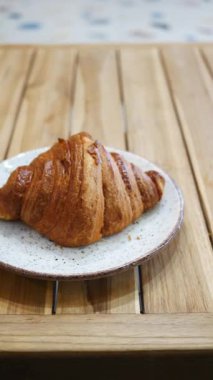 Lezzetli bir kruvasanın tadını çıkar Kafede bir kırsal tabakta dinlenirken.