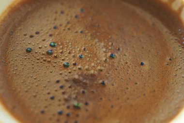 Yüzeyinde kabarcıklar olan koyu bir içecek bardağı doldurur..