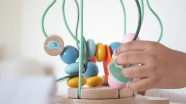 Çocuk, tahta labirent oyuncağına boncuk takıyor ve motor becerilerini geliştiriyor..