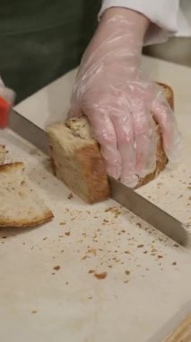 Bir fırıncı sıcak bir fırında taze ekmek dilimler..