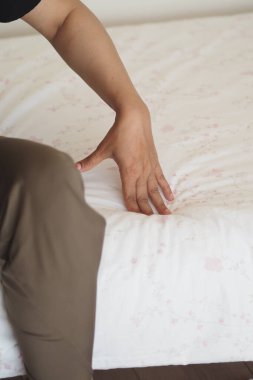 Bir insan çarşafları düzleştiriyor, temiz bir uyku alanı yaratıyor..