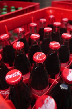 Kırmızı sandıklara düzgünce istiflenmiş kola dolu klasik cam şişeler..