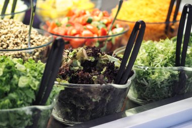 Çeşitli taze salatalar ve malzemeler yemek seçimi için düzenlenmiştir..