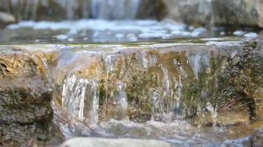 Pürüzsüz taşların üzerine dökülen berrak su manzarasının tadını çıkar..