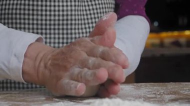 Becerikli eller, rahat bir mutfakta, ahşap bir masada hamur işi yapar..