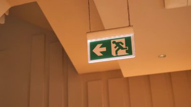 Aydınlatılmış bir çıkış işareti sol tarafta, güvenli bir yol gösteriyor.