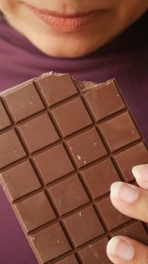 Birisi çikolatayı ısırıyor, zenginliğin tadını çıkarıyor..