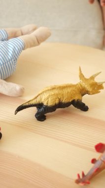 Çocuk eliyle renkli bir oyuncak dinozor seçiyor. .