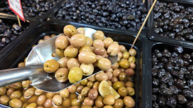 Müşteriler çeşitli zeytinlerle dolu bir market tezgahını keşfediyorlar..