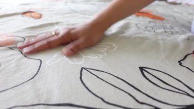 Bir el yumuşak dokunuşlu kumaş sergiliyor sakinleştirici renkler ve desenler.