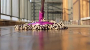 Bir insan ahşap zemini paspaslayarak toprağı ve tozu etkili bir şekilde temizler..