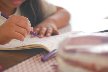 Küçük çocuk evde renkli kalemlerle çizim yapmaya odaklanıyor.