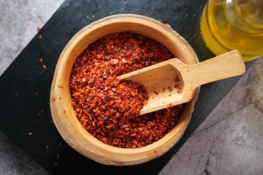 Parlak kırmızı biber taneleri bir kepçeyle ahşap bir kasede otururlar, baharata hazır..