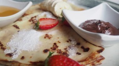 Çilek, muz ve çikolatayla servis edilen taze kreplerin tadını çıkarıyorum..