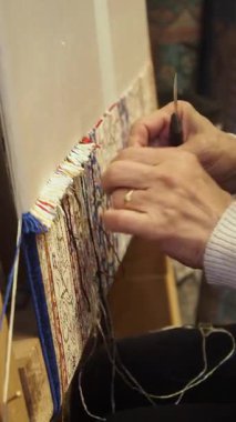 Bir zanaatkar hünerli bir şekilde örgü örerek renkli iplikler örer..