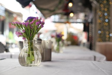 Vazodaki taze çiçekler açık alandaki kafelerde bir masa süslüyor..