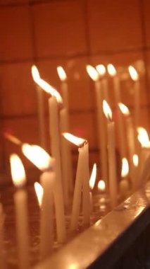 Sıcak ışıkta yanan bir çok mumdan alevler yavaşça yanıp sönüyor..