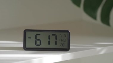 Dijital bir saat, akşamın sıcak bir atmosferle yaklaştığı zamanı gösterir.