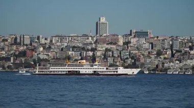 İstanbul 'un arka planında silueti olan bir feribot su üzerinde hareket ediyor.