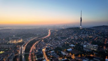 Gün batımında aşağıdaki işlek yollarla bir şehrin ufuk çizgisi görüntüsü.