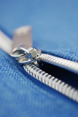 Metalik bir fermuara detaylı bir bakış mavi kumaşı yapıştıran, sergilenen tasarım.