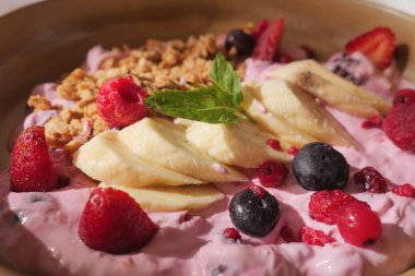 Yoğurt, böğürtlen, muz ve granola dolu renkli bir kase..