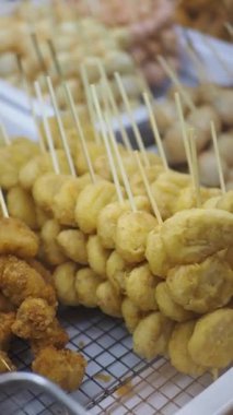 Lezzetli altın aperatifler canlı bir cadde pazarında şişler üzerine istiflenir..