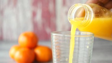 Parlak portakal suyu taze portakalların yanındaki bardağa dökülür..