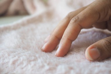 Bir el yumuşak pembe bir kumaşı nazikçe okşar..