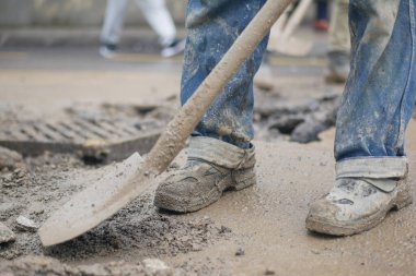 Bir işçi gün içinde işlek bir şehir caddesinde kazmak için bir kürek kullanır..