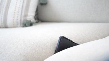 Bir telefon rahat bir koltuğun yastıklarının arasına sıkışmış..