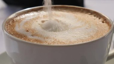 Bir kahve bardağına şeker dökmeye yakın çekim ,