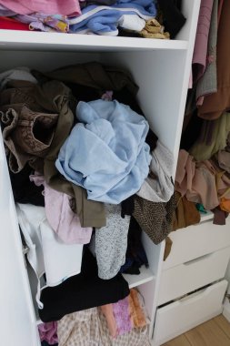 Parlak ışıklandırılmış kıyafet ve kumaş karışımı bir gardırop..