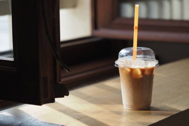 Ferahlatıcı bir buzlu kahve pencerenin yanındaki güneşli masaya konur..