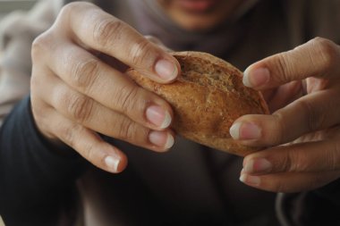 Sıcak bir ortamda otururken bir insan sıcak bir ekmek rulosu tutar..