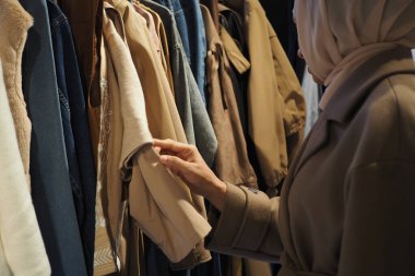 Bir kadın bir butikte şık kıyafetleri karıştırıyor..